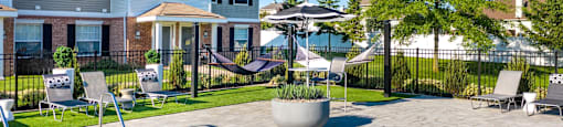a swimming pool with chairs and umbrellas in front of a house