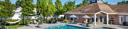 a swimming pool with lounge chairs in front of a building with a resort style pool