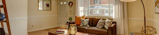 A living room with a couch, coffee table, and a window with curtains.