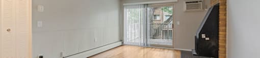 a living room with a hardwood floor and a sliding glass door to a balcony