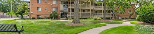 a building with a green lawn and trees and a sidewalk
