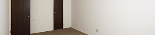 Second Bedroom with beige carpeting, and two closed doors to closet and outside of bedroom