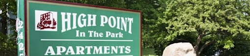 Green High Point in the Park monument sign - underneath smaller sign stating walk ins welcome surrounded by greenery and rocks.