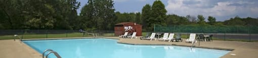 Exterior pool surrounded by trees and pool chairs