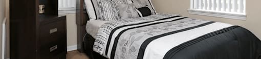 Black and white bedspread next to dresser
