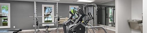 A spacious gym with a treadmill, weights, and a bench.