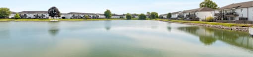 A serene lake surrounded by buildings and a clear blue sky.