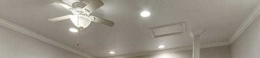 A room with a ceiling fan and carpeted floor.