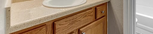 A bathroom with a sink, mirror, and wooden cabinets.