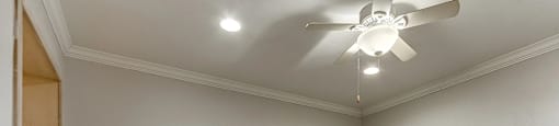 A room with a ceiling fan and carpeted floor.