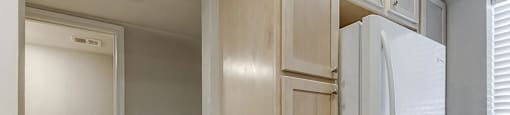 A white refrigerator is in a kitchen with wooden cabinets.