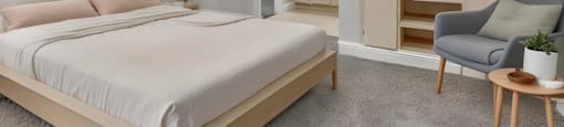 A bedroom with a large bed and a chair.