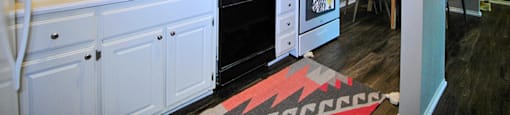 A kitchen with white cabinets and a black clock on the wall.