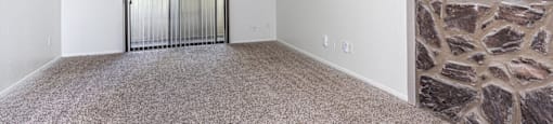 A room with a carpeted floor and a stone fireplace.