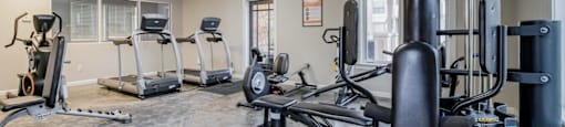 A gym with a variety of equipment including treadmills, weights, and exercise machines.