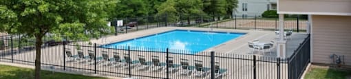 A pool surrounded by a black fence and trees.