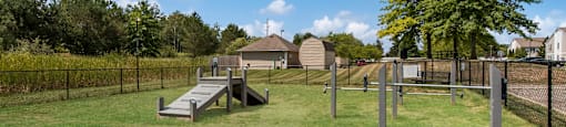 a fenced in dog park with a ramp and a fence
