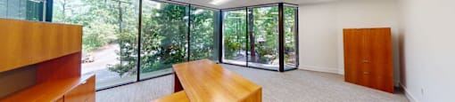 A room with a long table and chairs with a view of the outside.
