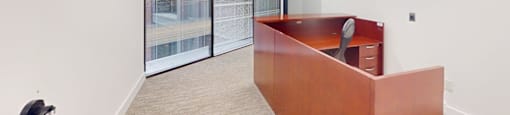 A room with a brown desk and a window with blinds.