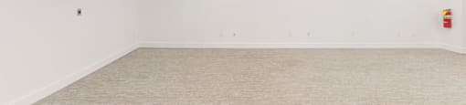 A large empty room with a carpeted floor and white walls.