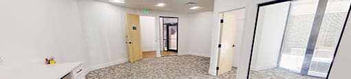 A spacious office room with a carpeted floor and white walls.