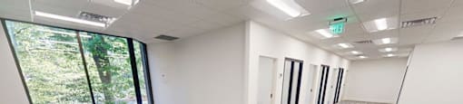 A spacious office room with carpeted flooring and large windows.