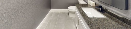 A bathroom with a toilet, sink, and mirror.