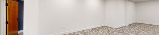 A room with a carpeted floor and a door on the left.