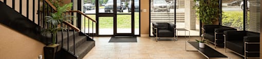 A hallway with black furniture and a glass door leading outside.