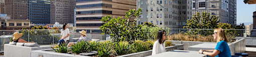 Two women are sitting at a table on a rooftop patio.