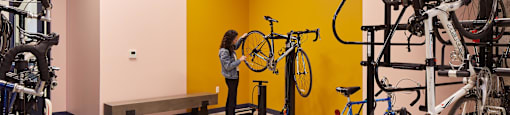 A woman is standing in a room with a yellow wall and several bicycles.