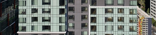 A modern building with glass windows and balconies is seen from a high vantage point.