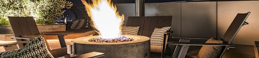 A fire pit in the middle of a patio surrounded by chairs.