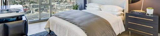 A modern bedroom with a large bed and a view of the city.