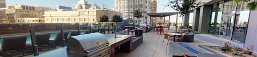 A rooftop patio with tables and chairs and a grill.