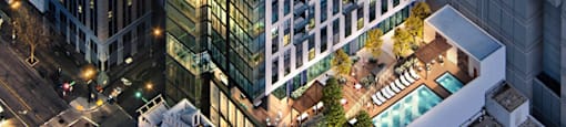 A tall building with a green roof is surrounded by other buildings.