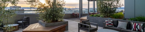 A rooftop patio with a table, chairs, and a bench.