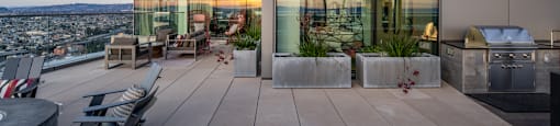A modern building with a glass facade and a rooftop terrace with seating and plants.