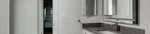 A bathroom with a sink, mirror and cabinet.