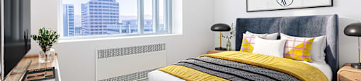 A modern bedroom with a large bed and a city view through the window.