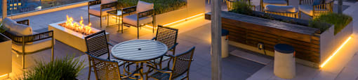 A rooftop patio with a table, chairs, and a TV.