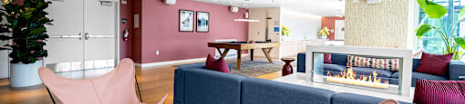 A living room with a pink chair and a white table.