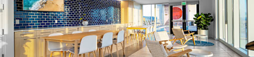 A room with a long table and chairs with a blue tiled wall behind it.