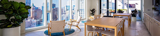 A modern kitchen with a dining table and chairs in front of a large window overlooking a cityscape.