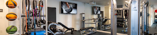 A gym with a variety of equipment including a treadmill, weights, and a bench.