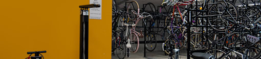 A yellow wall with a bike rack full of bicycles.