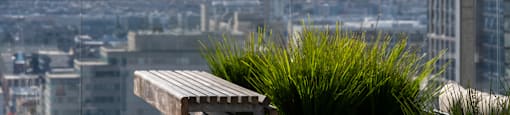 A row of grey concrete bins with black lids are lined up on a rooftop terrace.