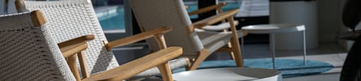 A row of wicker chairs are lined up on a patio.