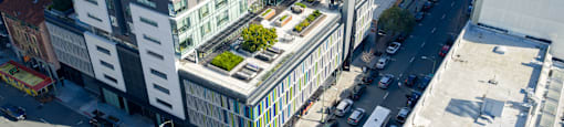 A tall building with a green roof is surrounded by other buildings and busy streets.