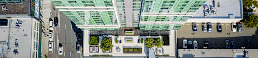 A modern building with a glass facade and a pool on the top floor.